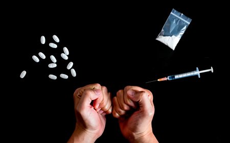Руки находятся на черном фоне с наркотиками